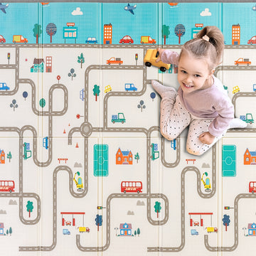 A toddler playing with a toy car on a city-themed playmat, driving along other vehicles pictures on colorful roads and buildings. The soft, cushioned mat features streets and landmarks for imaginative play.